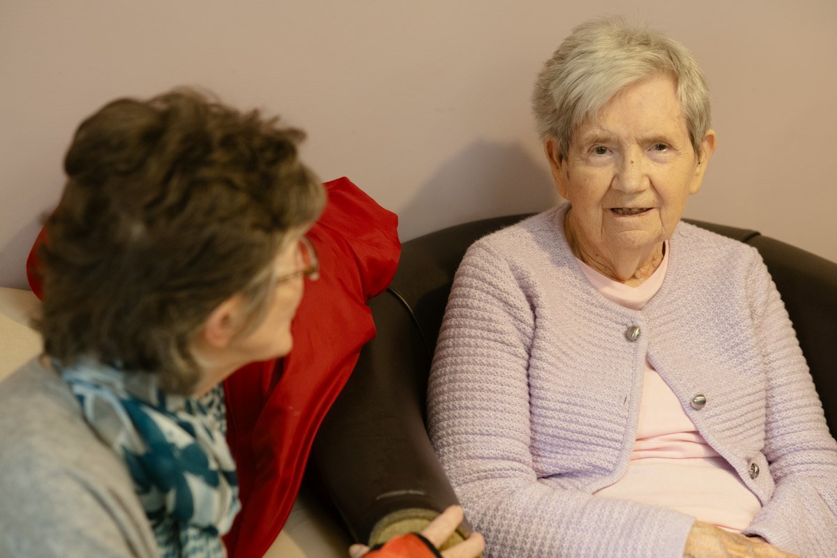 Two elderly residents sitting and chatting together